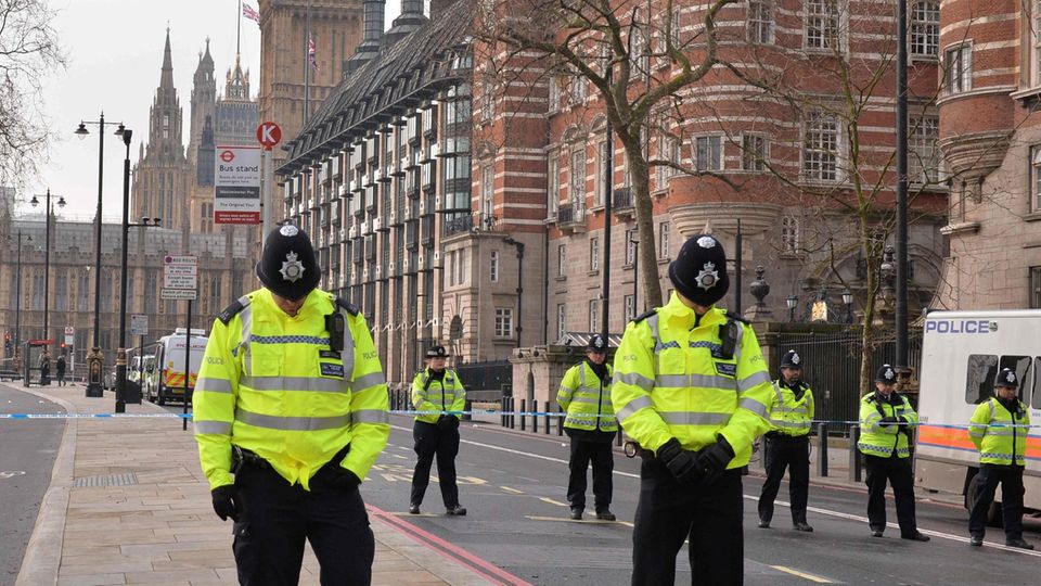 Während der Schweigeminute für die Opfer des Anschlags von London stehen Polizisten mit gesenkten Köpfen still