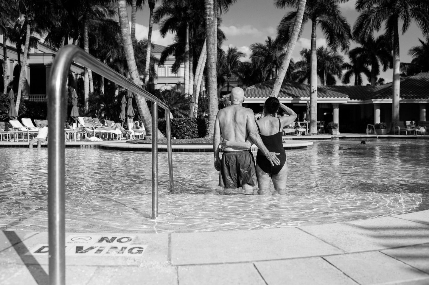 Die Eltern stehen im Swimmingpool mit dem Rücken zur Kamera