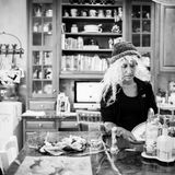 Laurel mit blond gelockter Perücke und Mütze