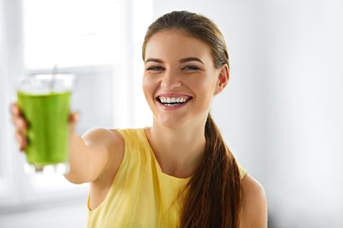Eine Frau trinkt einen grünen Smoothie.