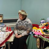 Weihnachtsbazar in Swaffham, Norfolk. Eine Rentnerin bessert sich ihre Pension durch den Verkauf von Nippes auf.