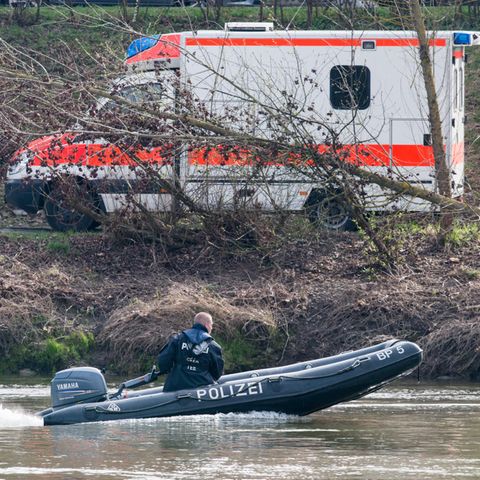 Ein Schlauchboot der Polizei auf der Donau, am Ufer steht ein Rettungswagen