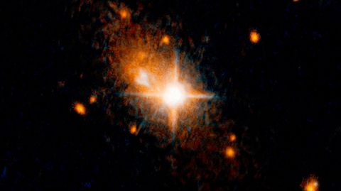 Die Aufnahme des "Hubble"-Weltraumteleskop zeigt den hellen Quasar (Bildmitte). Quasare sind normalerweise die Kerne aktiver Galaxien. Sie werden von einem zentralen Schwarzen Loch angetrieben. Die Schwarzen Löcher selbst lassen sich nicht beobachten, aber die Quasare strahlen meist heller als eine ganze Galaxie.