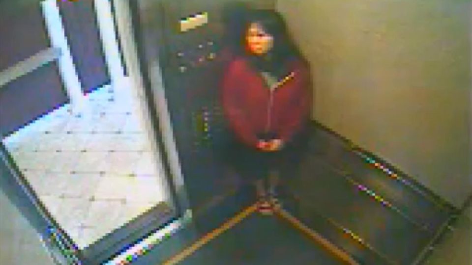 Die dunkelhaarige Elisa L., eine Frau mit roter Jacke in einem Fahrstuhl.