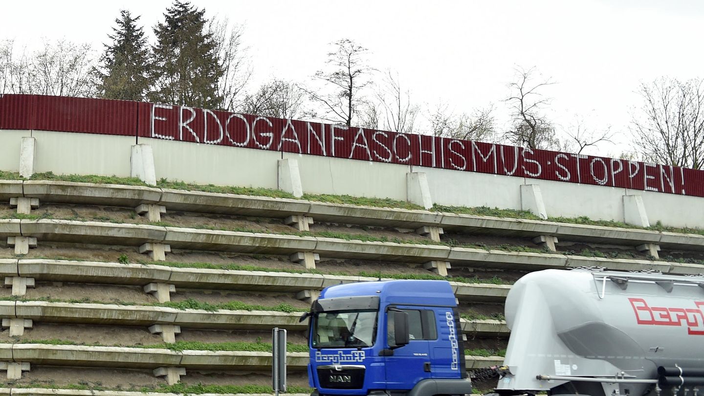 Der Schriftzug "Erdoganfaschismus stoppen!" an einer Lärmschutzwand einer Autobahn, davor ein vorbeifahrender Sattelschlepper.