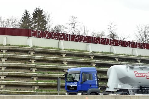 Der Schriftzug "Erdoganfaschismus stoppen!" an einer Lärmschutzwand einer Autobahn, davor ein vorbeifahrender Sattelschlepper.