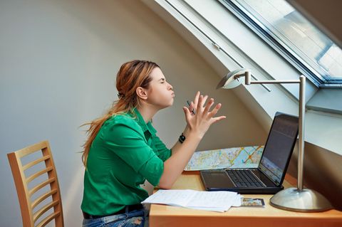 Eine Frau sitzt frustriert vor ihrem alten, dicken Notebook