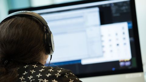 Filesharing: Eine Frau mit Kopfhörern sitzt vor einem Computer.