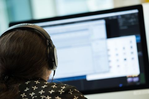 Filesharing: Eine Frau mit Kopfhörern sitzt vor einem Computer.