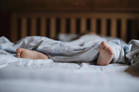 Füße eines schlafenden Kindes im Bett (Symbolbild für Resignation Syndrome in Schweden)