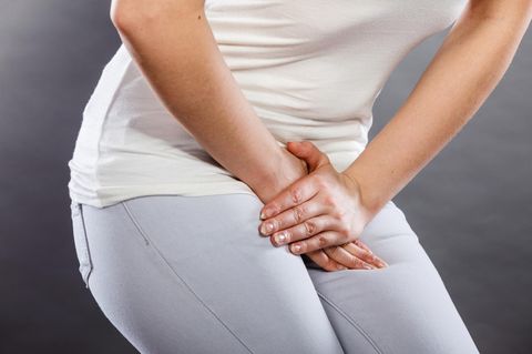 Eine Frau hat Schmerzen und fasst sich an den Bauch.