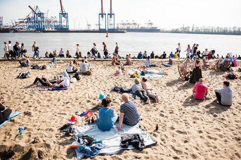 bei gutem Wetter sitzen und liegen Menschen am Hamburger Elbstrand