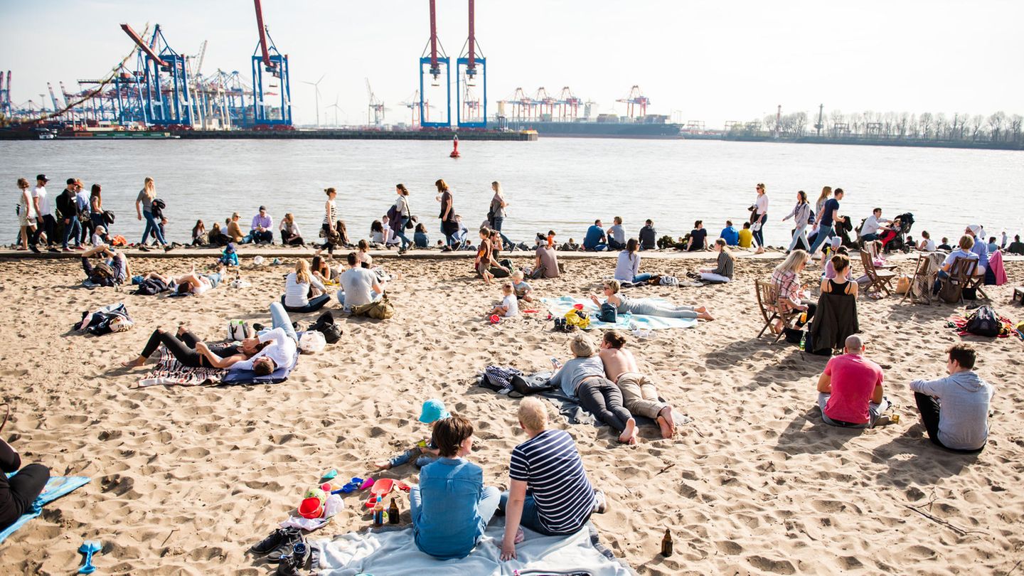 bei gutem Wetter sitzen und liegen Menschen am Hamburger Elbstrand