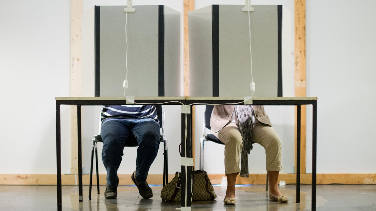 Ein Mann und eine Frau sitzen in einer Wahlkabine