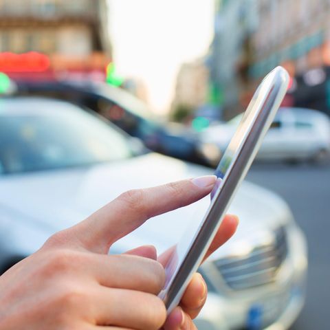 Eine Frau bestellt ein Taxi mit ihrem Smartphone