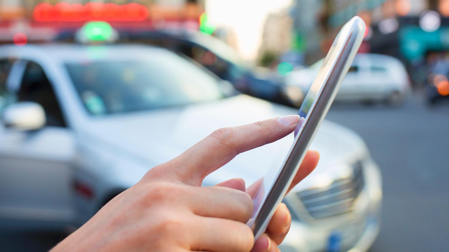 Eine Frau bestellt ein Taxi mit ihrem Smartphone