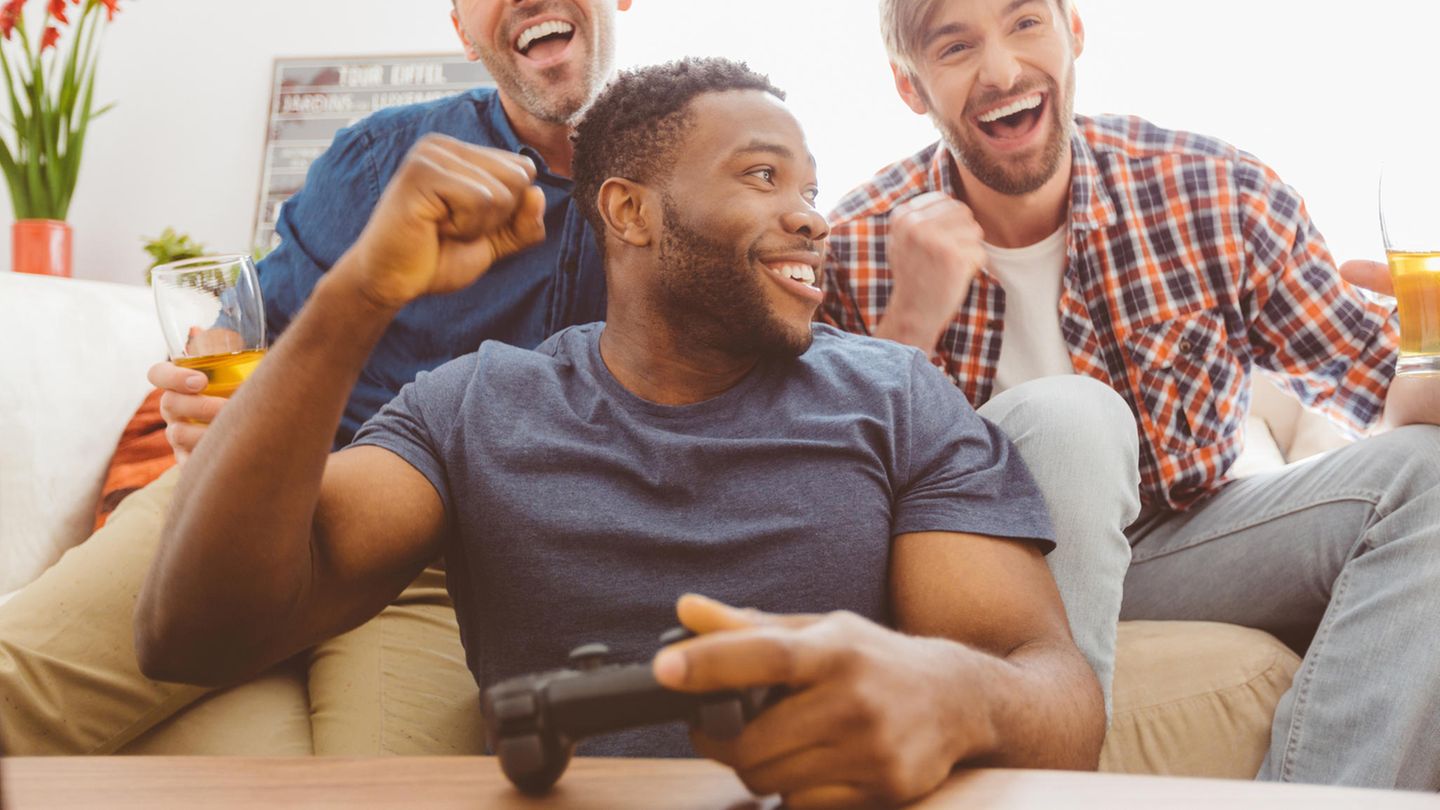 Drei Männer spielen gemeinsam an der Playstation 4