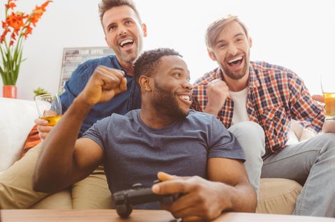 Drei Männer spielen gemeinsam an der Playstation 4