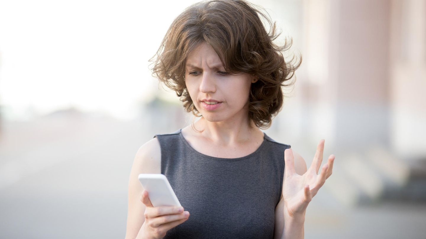 Eine Frau schaut verärgert auf ihr Smartphone