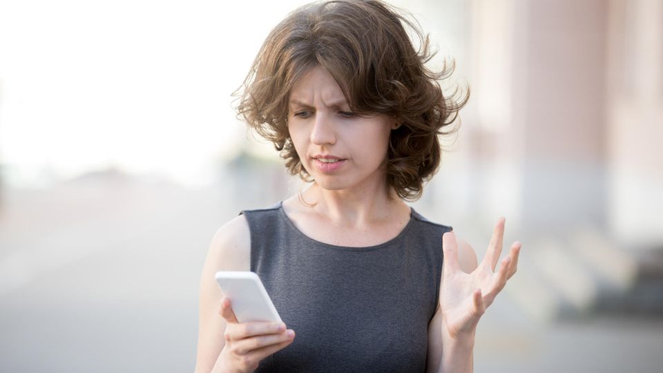 Eine Frau schaut verärgert auf ihr Smartphone