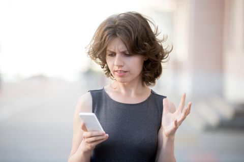Eine Frau schaut verärgert auf ihr Smartphone