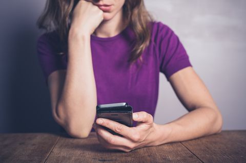 Eine Frau starrt entsetzt auf ihr Smartphone