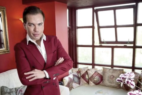 In weinrotem Anzug steht Rodrigo Alves mit verschränkten Armen da und lächelt mit starrer Mimik in die Kamera.