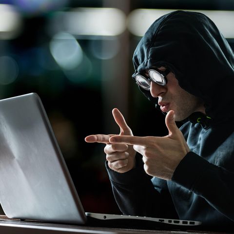 Ein lächerlich verkleideter Hacker sitzt vor einem Laptop