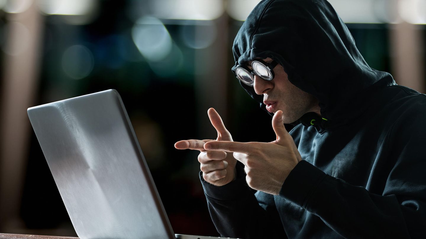 Ein lächerlich verkleideter Hacker sitzt vor einem Laptop
