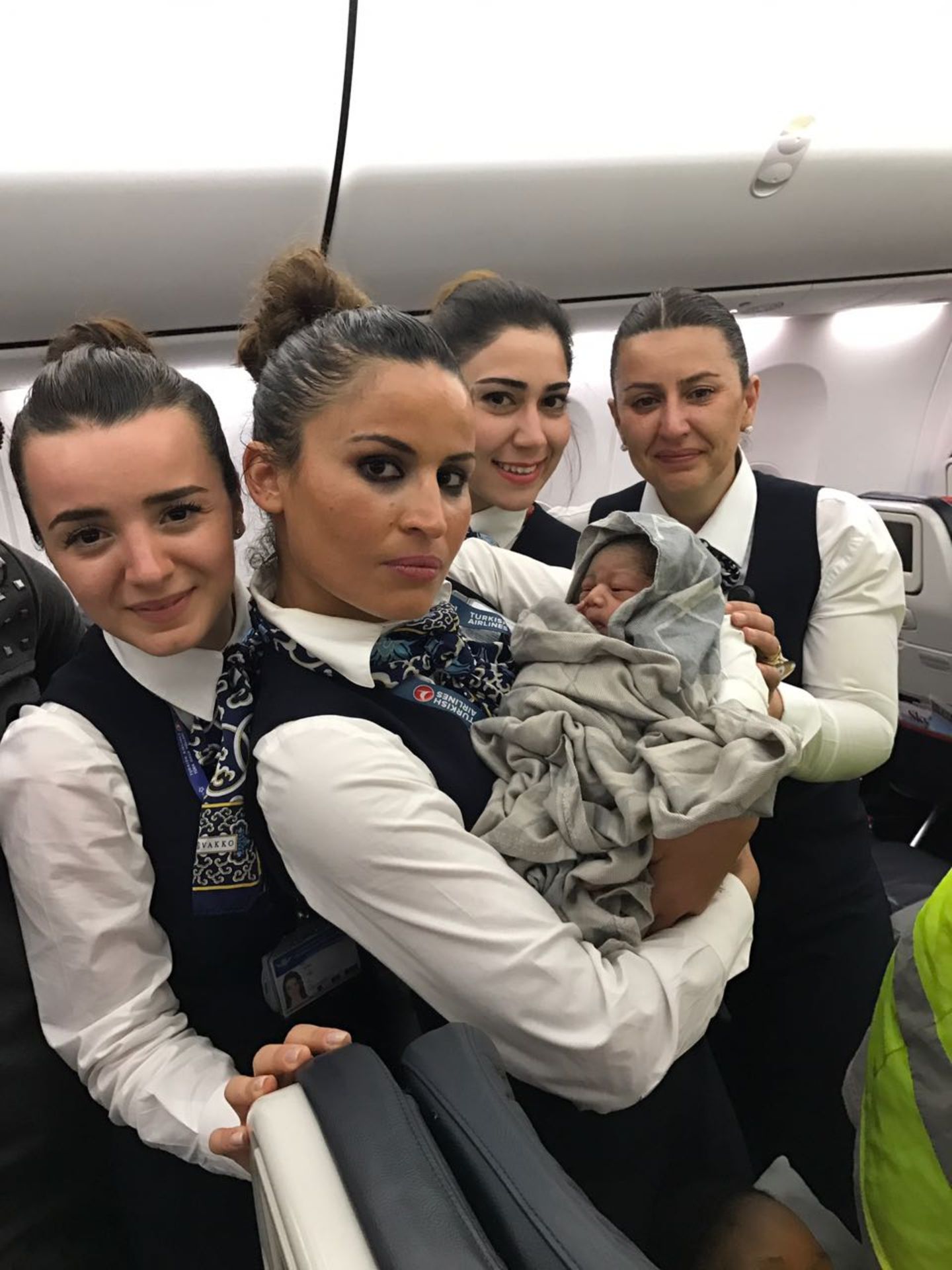 Himmlischer Geburtsort in einem Flugzeug: Die Flugbegleiter halten die kleine in Decken gewickelte "Kadiju" im Arm.