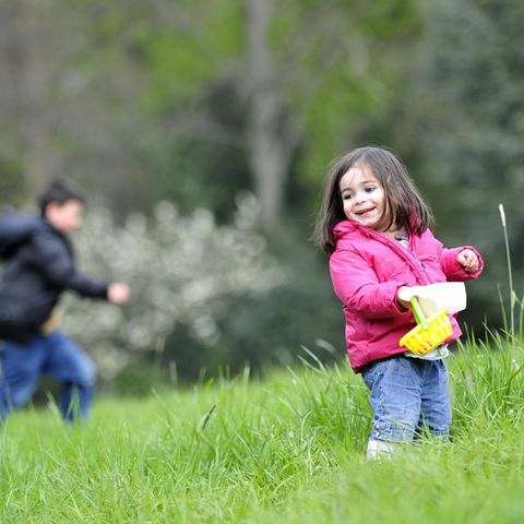 Zwei Kinder suchen auf einer Wiese Ostereier. Das Wetter an Ostern 2017 wird ungemütlich.