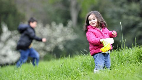 Zwei Kinder suchen auf einer Wiese Ostereier. Das Wetter an Ostern 2017 wird ungemütlich.