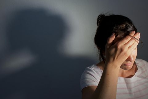 Frau hält sich vor Schmerz die Hand an den Kopf