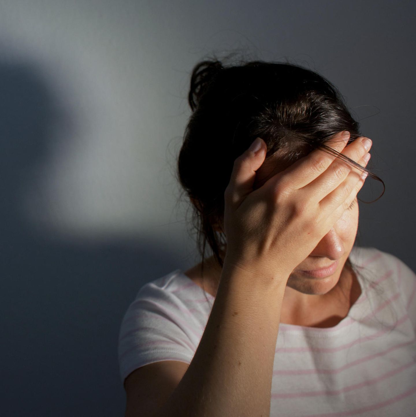 Frau hält sich vor Schmerz die Hand an den Kopf