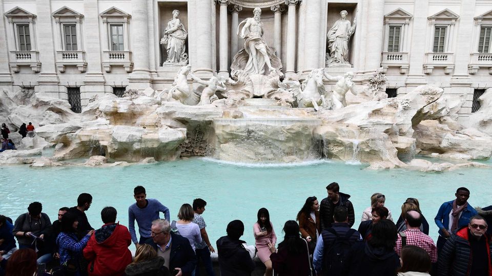 Touristen stehen vor dem Trevi-Brunnen in Rom