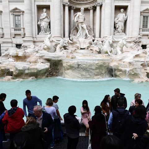 Touristen stehen vor dem Trevi-Brunnen in Rom