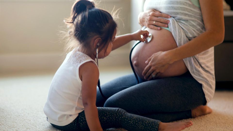 Mädchen betastet den Bauch ihrer schwangeren Mutter