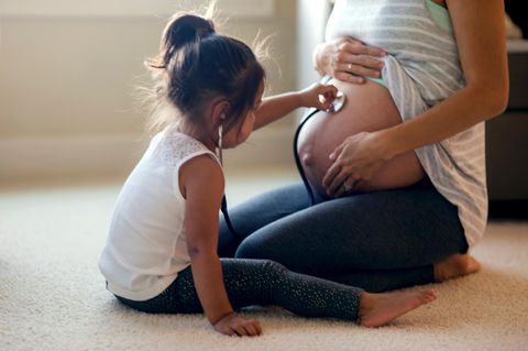 Mädchen betastet den Bauch ihrer schwangeren Mutter