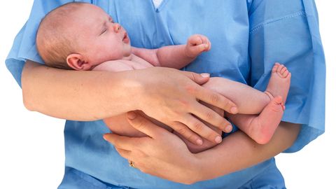 Eine Hebamme hält ein Baby auf dem Arm