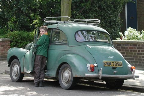 Junge steht neben einen Auto und lacht