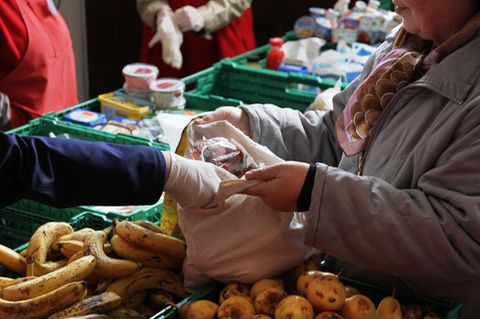 Ein Berliner Tafel-Mitarbeiter packt Obst in eine Tragetasche.