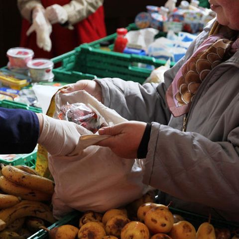 Ein Berliner Tafel-Mitarbeiter packt Obst in eine Tragetasche.