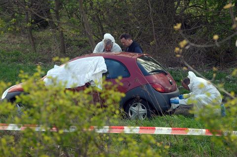Männer in weißen Overalls untersuchen einen roten Ford Ka - Weißes Tuch deckt den Vorderbereich ab