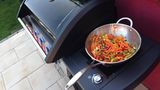 Männer am Grill sind ja oft eher fleischfixiert. Ein dezenter Hinweis zu mehr Vielfalt könnte das Geschenk einer Wok-Pfanne sein.  Der Grill muss dafür entweder eine Aussparung auf dem Grillrost haben oder einen Seitenkocher am Gasgrill. Unverwüstlicher Edelstahl (einschließlich Griff) ist eine gute Materialwahl und ein Durchmesser von rund 30 dann Zentimetern sollte für alle Grills passen. Manche Wokpfannen sind ausladender und passen unter Umständen dann nur noch auf den Seitenkocher, wenn die Grillhaube geöffnet ist. Viele Hersteller bieten für ihre Grills eigene Wok-Pfannen an. 