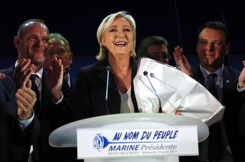 Marine Le Pen steht bei der Präsidentschaftswahl mit einem Strauß Blumen im Arm lächelnd hinter einem Rednerpult