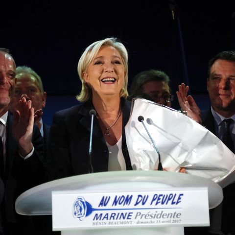Marine Le Pen steht bei der Präsidentschaftswahl mit einem Strauß Blumen im Arm lächelnd hinter einem Rednerpult