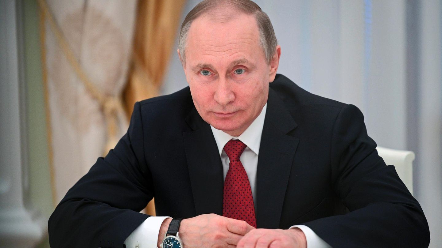 Russlands Präsident Wladimir Putin sitzt auf seine Unterarme gestützt im dunklen Anzug am Schreibtisch