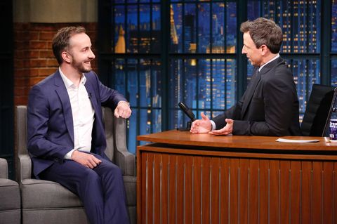 Jan Böhmermann sitzt links auf einem Sessel, während Moderator Seth Meyers hinter seinem hölzernen Schreibtisch sitzt