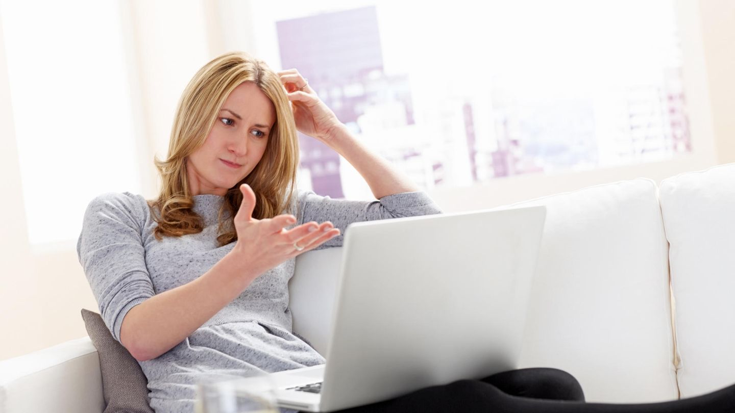 Eine Frau schaut frustriert auf ihren Laptop