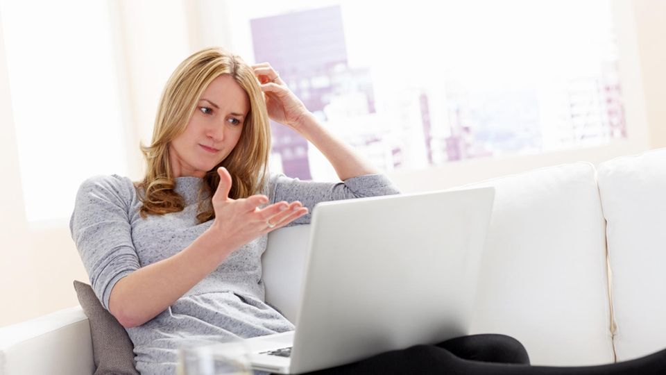 Eine Frau schaut frustriert auf ihren Laptop